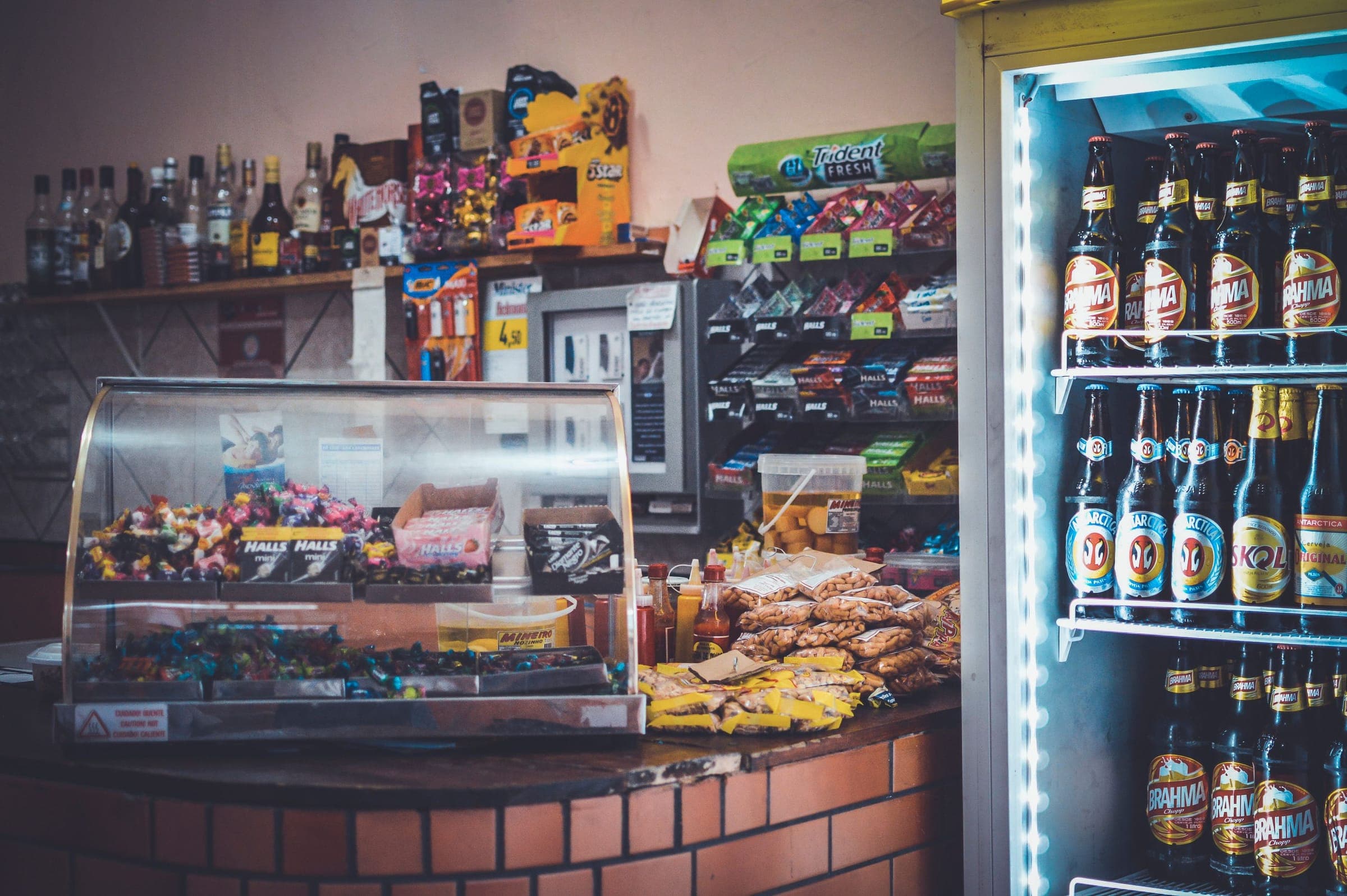 Convenience store counter with a curved glass candy case beside a drinks cooler