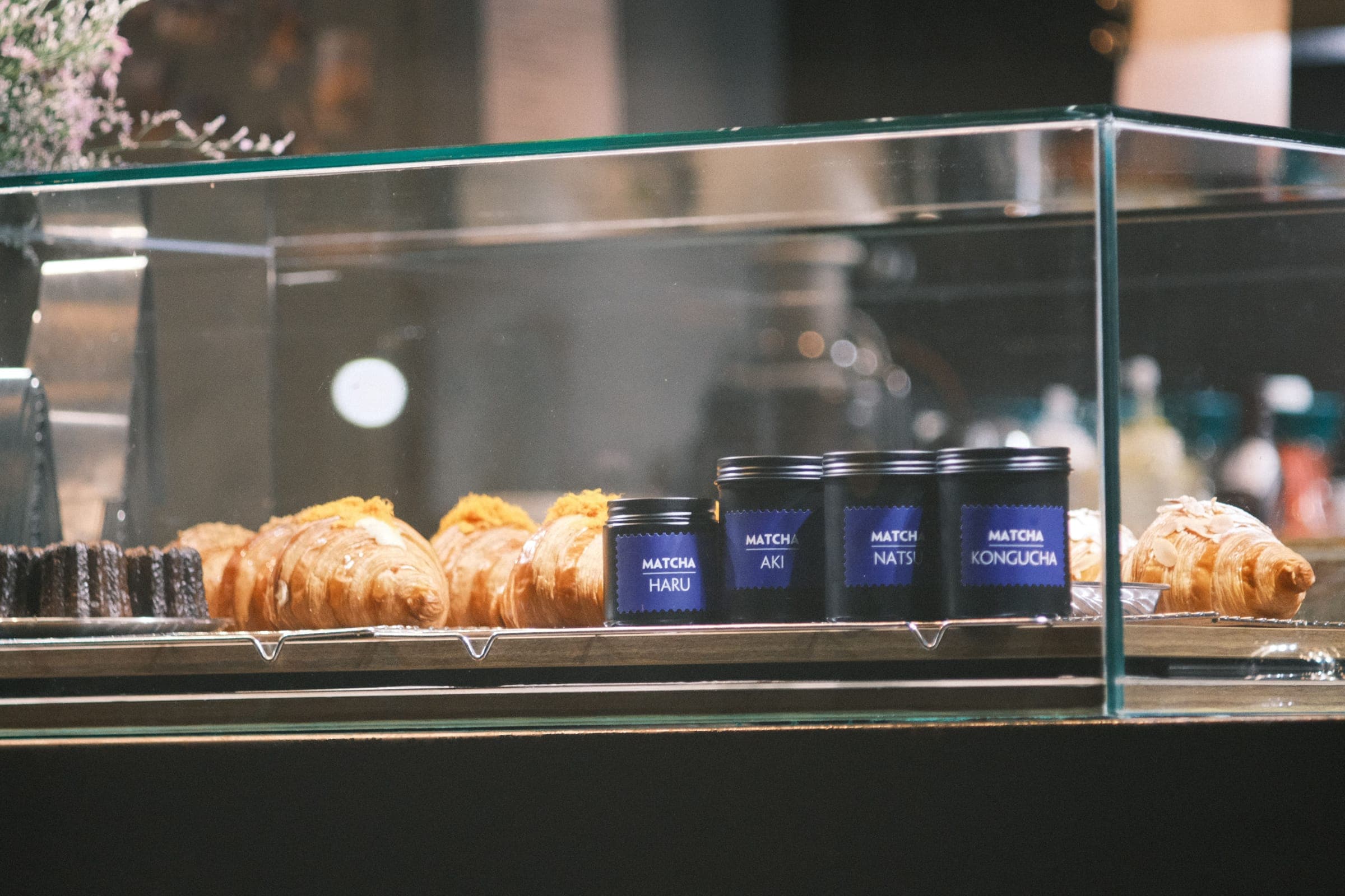 Frameless glass countertop case holding pastries and tea tins